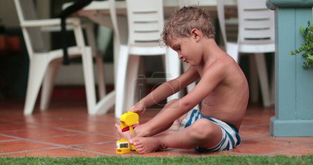 Photo for Kid playing by himself outside with building blocks - Royalty Free Image