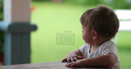 Téléchargez les photos : Baby standing holding furniture upset. Angry toddler infant complaining mood - en image libre de droit