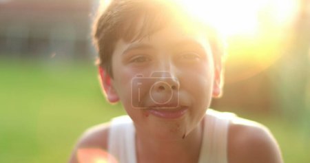 Photo for Handsome young boy child smiling to camera outside during sunset golden hour time - Royalty Free Image