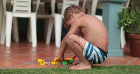 Photo for Cute child boy playing by himself in home balcony with building blocks - Royalty Free Image
