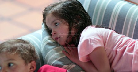 Photo for Children laid on sofa at night watching television screen - Royalty Free Image