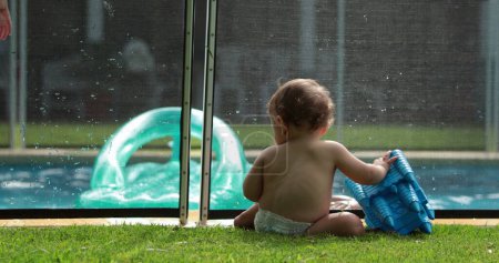 Foto de Familia en la piscina, bebé en primer plano y niños en segundo plano jugando dentro del agua - Imagen libre de derechos