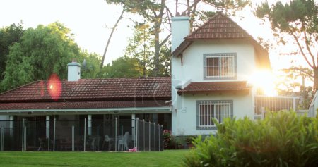 Téléchargez les photos : Extérieur de la maison résidentielle pendant l'heure dorée avec coucher de soleil à éclat de lentille - en image libre de droit