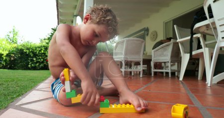 Photo for Kid playing by himself outside with building blocks - Royalty Free Image