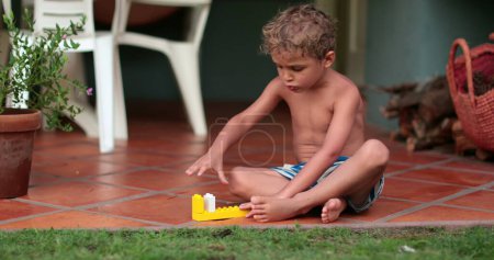 Foto de Un niño imaginativo jugando solo afuera. Niño juega con juguetes en casa - Imagen libre de derechos