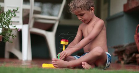 Photo for Imaginative child playing with building blocks outside. Toddler boy plays with pieces of construction - Royalty Free Image