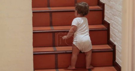 Foto de Baby climbing and standing on home stairs - Imagen libre de derechos