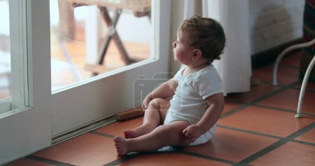 Téléchargez les photos : Bébé mignon voulant quitter la maison, tout-petit appuyé sur la fenêtre, bébé voulant à l'extérieur - en image libre de droit