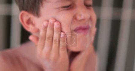 Téléchargez les photos : Enfant garçon étalant de la crème solaire sur son visage. Enfant appliquant crème solaire lotion pour lui-même - en image libre de droit