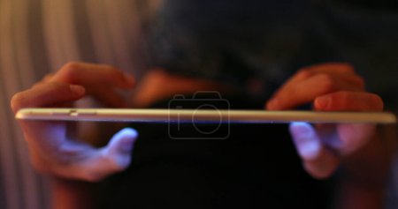 Photo for Child using tablet device at night, closeup of kid hand and fingers touching screen - Royalty Free Image