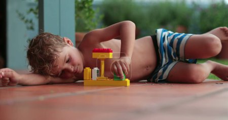 Foto de Niño pequeño jugando solo con bloques de bullicio afuera durante el día de verano - Imagen libre de derechos