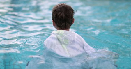 Téléchargez les photos : Enfant avec serviette de piscine à l'intérieur de l'eau s'amuser pendant la saison estivale - en image libre de droit