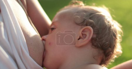 Foto de Bebé amamantando en madre pecho fuera - Imagen libre de derechos