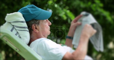 Photo for Candid man reading newspaper outdoors. Candid casual real life senior pelrson reading news outside - Royalty Free Image