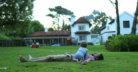 Téléchargez les photos : Bébé et père ensemble collage couché dehors sur l'herbe, papa et bébé embrasser - en image libre de droit