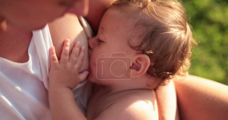 Photo for Baby suckling on mother breast outside at park - Royalty Free Image