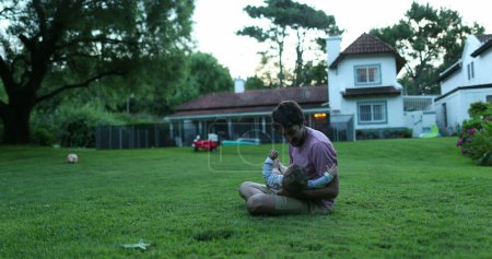 Téléchargez les photos : Père et fils bébé ensemble dans le jardin extérieur de la maison - en image libre de droit