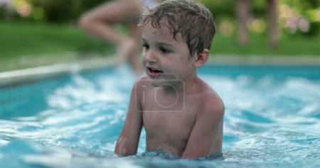 Téléchargez les photos : Enfant heureux tout-petit garçon à l'intérieur de l'eau de la piscine s'amuser - en image libre de droit