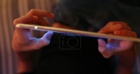 Téléchargez les photos : Enfant tenant tablette dispositif la nuit tactile jeu d'écran, vu d'en haut - en image libre de droit