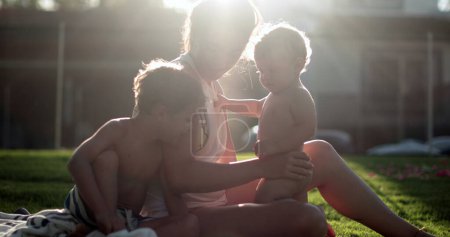 Photo for Family outside in home garden with sunlight lens-flare, dreamy scene of mother with children - Royalty Free Image