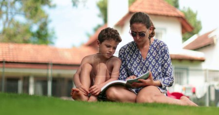 Téléchargez les photos : Mère apprenant à lire aux enfants. Parent tutorat garçon frustré - en image libre de droit