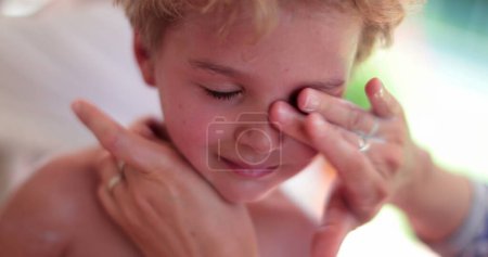 Foto de Mamá aplica crema solar a la cara del niño - Imagen libre de derechos
