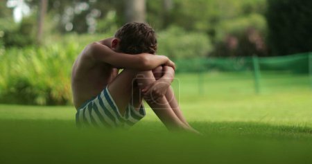 Photo for Sad upset child boy with head down in outdoor park - Royalty Free Image