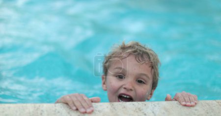 Téléchargez les photos : Petit garçon sortant de l'eau au bord de la piscine. Corps de levage d'enfant piscine - en image libre de droit