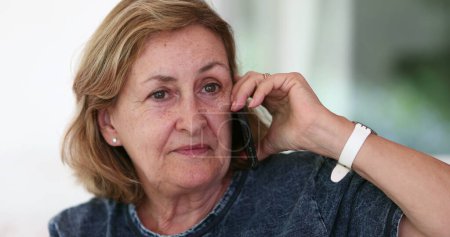 Foto de Older woman listening attentively on phone conversation - Imagen libre de derechos