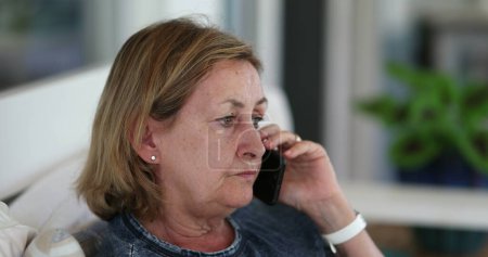 Téléchargez les photos : Older woman listening to conversation on cellphone - en image libre de droit