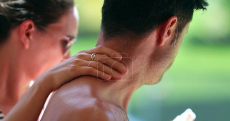 Photo for Wife applying sunscreen to husband body. Woman rubbing sunblock lotion to partner skin - Royalty Free Image
