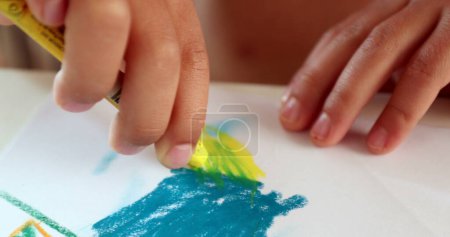 Foto de Manos de niño dibujando sobre papel con lápiz de colores. Primer plano niño mano dibuja con lápices de colores amarillos - Imagen libre de derechos