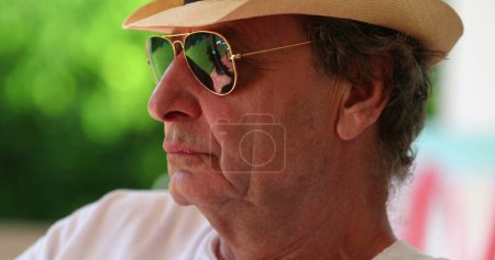 Photo for Cool senior man wearing sunglasses and hat relaxing outdoors. Pensive retired older person - Royalty Free Image
