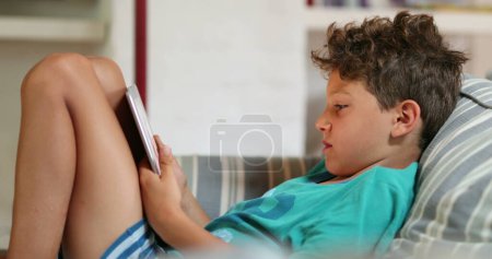 Foto de Los niños en casa usando el dispositivo de tableta en el sofá casero - Imagen libre de derechos