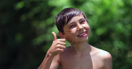 Foto de Niño dando pulgares afuera. Feliz joven señalando positivo pulgar afirmativo hacia arriba - Imagen libre de derechos