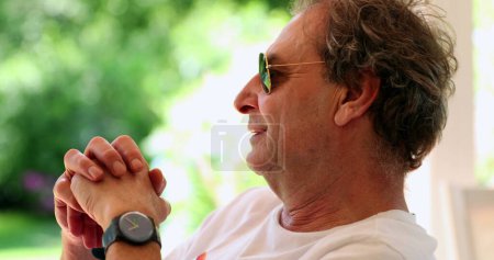 Foto de Relaxed smiling older man thinking outside wearing sunglasses - Imagen libre de derechos