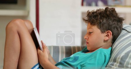 Photo for Children at home using tablet device on home sofa - Royalty Free Image