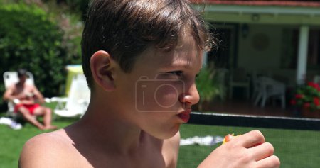 Téléchargez les photos : Un gamin qui mange des fruits de pêche dehors. Collation pour enfants aliments sains - en image libre de droit