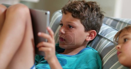 Téléchargez les photos : Enfants devant l'écran de la tablette à la maison - en image libre de droit