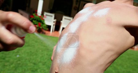 Photo for Father applying sunblock to child skin. Parent rubbing sunblock lotion to kid body, sun tan prevention - Royalty Free Image