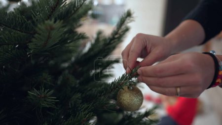 Foto de Primer plano mano femenina poner la decoración de la bola de Navidad en la rama del árbol - Imagen libre de derechos