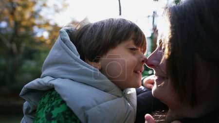 Foto de Feliz madre e hijo haciendo beso esquimal con la nariz de pie al aire libre con destello de luz solar. Maternidad estilo de vida concepto - Imagen libre de derechos