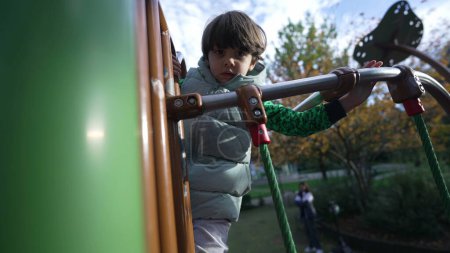 Foto de Niño escalando estuctura del patio al aire libre. Ejercicios activos para niños afuera. Niño deportivo - Imagen libre de derechos