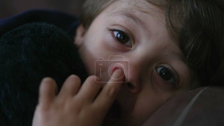 Foto de Nariz de niño recogiendo cara de cerca con el dedo. Un niñito reflexivo se mete en la nariz mientras se pierde en el pensamiento - Imagen libre de derechos