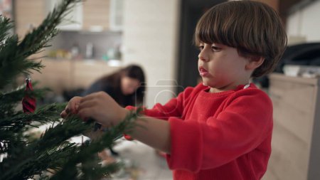 Foto de Un niño pequeño decorando el árbol de Navidad. Primer plano niño poner decoración de la bola - Imagen libre de derechos