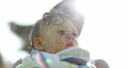 Foto de Lindo bebé envuelto en toalla en la luz del sol al aire libre - Imagen libre de derechos