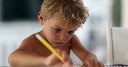 Téléchargez les photos : Dessin concentré pour tout-petit enfant sur papier avec stylo couleur - en image libre de droit