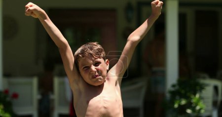 Foto de Niño levantando brazos en el aire en celebración. Emocionado joven levanta el brazo celebrando - Imagen libre de derechos