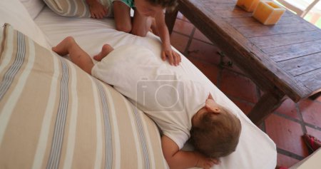 Téléchargez les photos : Bébé frère couché sur le canapé à la maison, moment de famille mignon tout-petit - en image libre de droit
