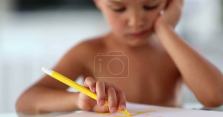 Téléchargez les photos : Petit garçon créatif esquissant sur papier avec stylo jaune - en image libre de droit